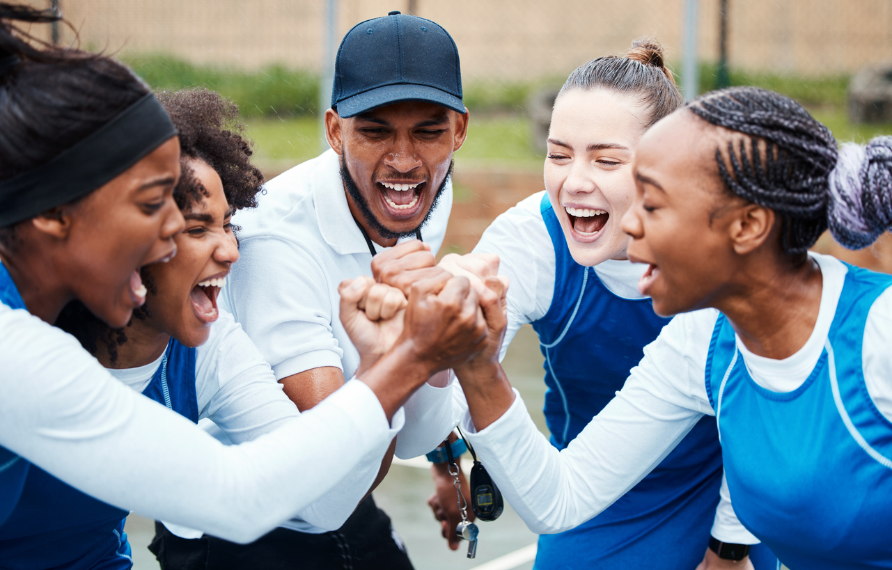 Fist, motivation or team support in netball training game screaming with hope or faith on sports court. Teamwork, fitness coach or group of excited athlete girls with pride or solidarity together