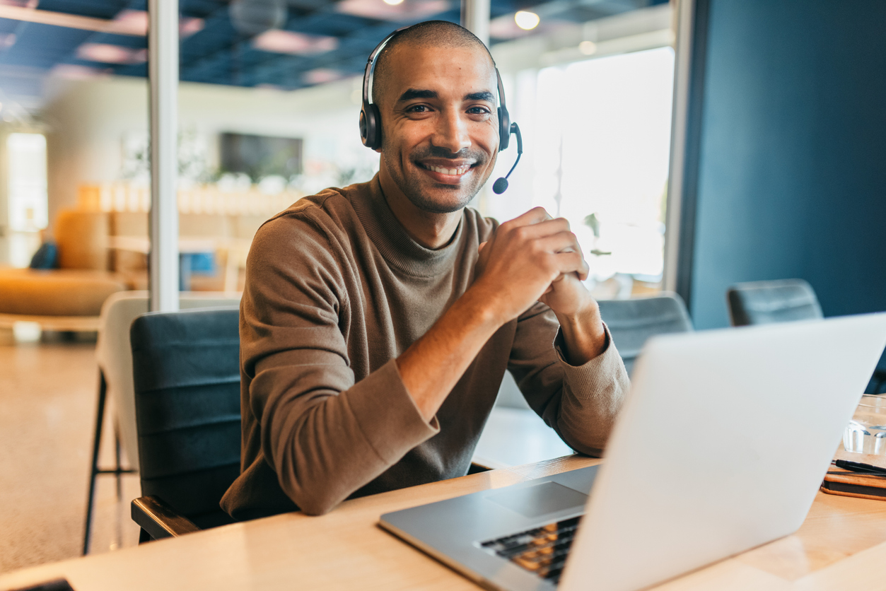 Confident businessman with headset, smiling cheerfully at camera in call center office